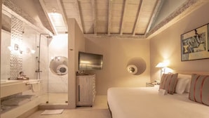 Een hotelkamer met een douche, een televisie, een bed en een wandklok.