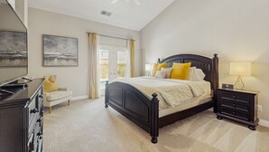 Ein Schlafzimmer mit Bett, Nachttisch, Kommode und Deckenventilator.