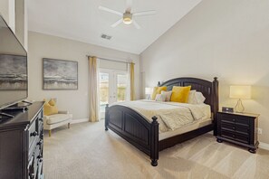 Een slaapkamer met een bed, nachtkastje, dressoir en plafondventilator.