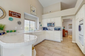 A spacious kitchen with white cabinetry, a large island, and a view to the dining area. - Airy retreat near dining with private pool, pool spa & kitchen - 3 BR - #066586 (La Quinta)