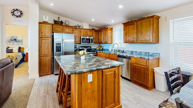 Una cocina amplia con armarios de madera, encimera de granito y electrodomésticos modernos.