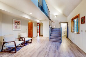 A spacious living area with a wooden floor, a staircase, and a view of the kitchen. - Charming Craftsman Escape Minutes from Snowbowl (Flagstaff)