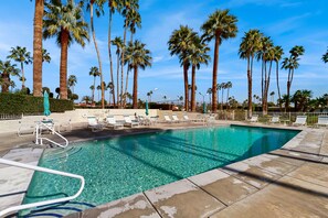 A swimming pool with clear water, surrounded by palm trees and lounge chairs. - Delightful and sophisticated condo with shared tennis, outdoor pool, & spa (Palm Springs)