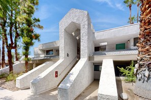 A modern building with a unique architectural design, featuring a central staircase and multiple balconies. - Lovely Palm Tree Retreat with Pools, Hot Tubs & Tennis | Near Golf & Dining (Palm Springs)