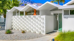 A modern building with a white exterior, a patterned fence, and a mountain in the background. - Charming & bright mid-century condo with shared pool - Free WiFi (Palm Springs)