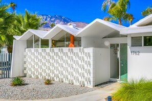 A modern building with a white exterior, a patterned fence, and a mountain in the background. - Charming & bright mid-century condo with shared pool - Free WiFi (Palm Springs)