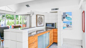 A modern kitchen with white cabinetry, a built-in microwave, and a glass-fronted cabinet. - Charming & bright mid-century condo with shared pool - Free WiFi (Palm Springs)
