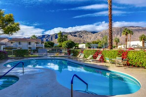 A swimming pool with lounge chairs and a view of mountains.