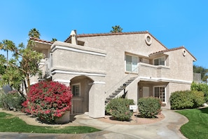 A two-story house with a stucco exterior, a front entrance with a door and window, and a staircase leading to the second floor.
