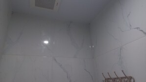 A bathroom with white marble walls and a ceiling vent. - OYO 95184 Ms Home Syariah (Tegal)