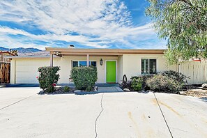 Une maison à deux étages avec une porte verte, un garage et une allée.