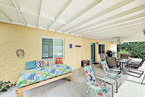 Un espace extérieur abrité comprenant un lit, des chaises, une table et un barbecue.
