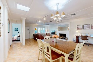 A spacious dining area with a wooden table and chairs, a chandelier, and a fireplace. - Movie Colony Oasis | Pool, Spa & Mountain Views | Near Downtown Palm Springs (Palm Springs)