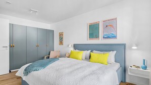 Ein Schlafzimmer mit Bett, Nachttisch, Kleiderschrank und zwei Wandbildern.