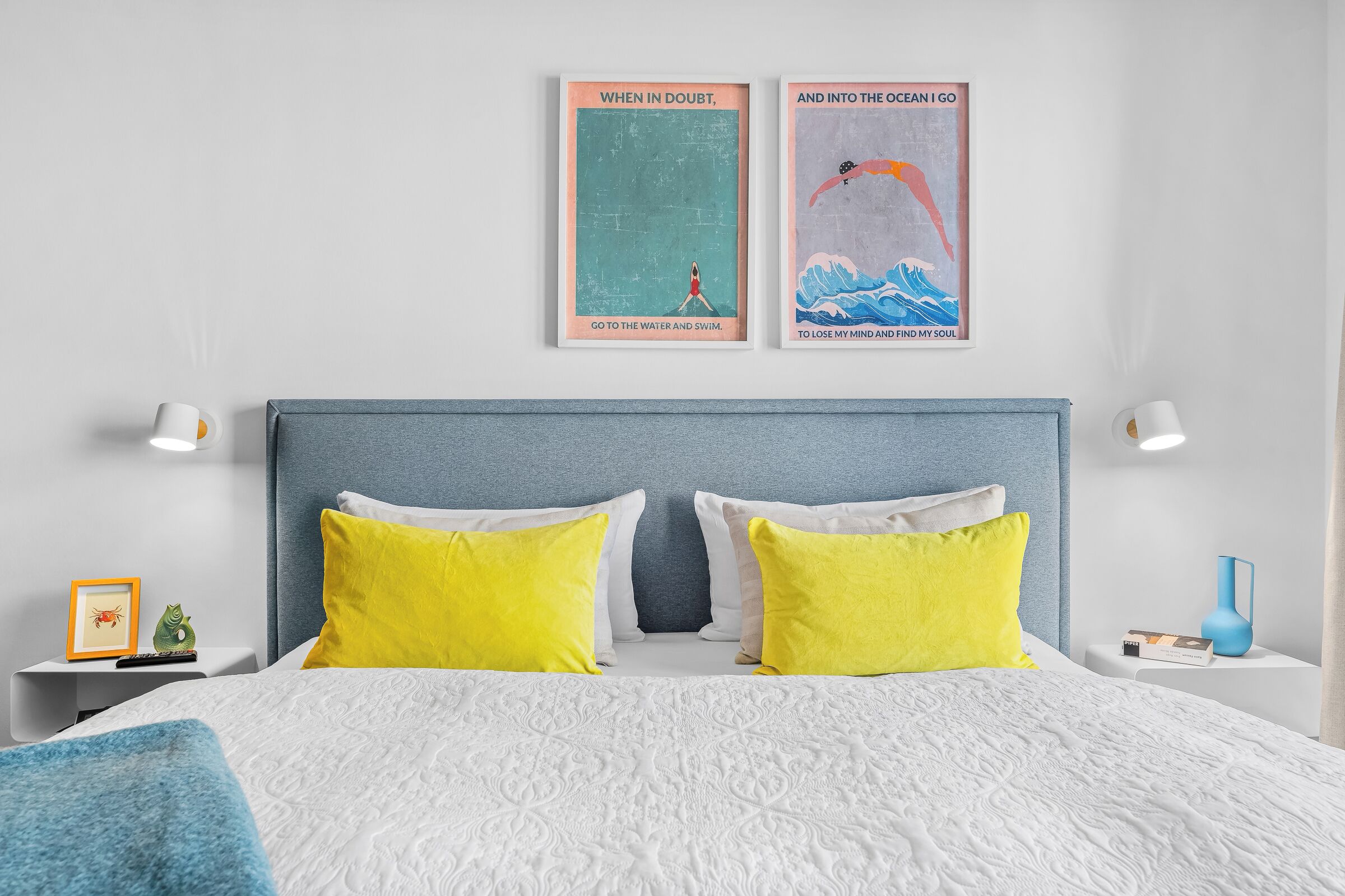 Ein Schlafzimmer mit Bett, zwei Kissen, einem Nachttisch, einem gerahmten Poster und einer Lampe.