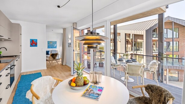 Ein modernes Interieur mit Essbereich, Küche und großen Fenstern.