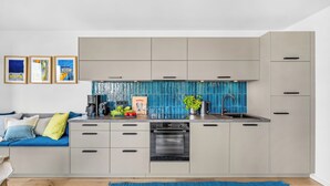 Eine moderne Küche mit grauen Schränken, einer blauen Spritzschutzwand und einer Kaffeemaschine.