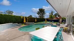 Ein Garten mit Pool, überdachter Terrasse und Gartenmöbeln.