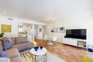 A modern living room with a sofa, coffee table, TV, and dining area. - Dog Friendly Mid-Century Villa at The Coco Cabana with Pool, Spa & Tennis Courts (Palm Springs)