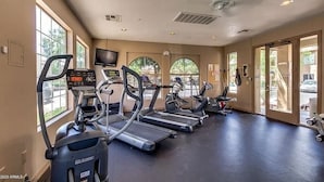 Un gimnasio con cintas de correr, bicicletas estáticas y una pantalla de televisión.