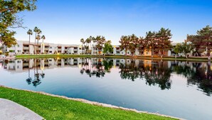 Un hotel con piscina reflejante, arquitectura moderna y césped cuidado.