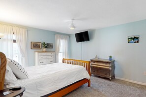 A bedroom with a bed, dresser, TV, and a ceiling fan. - Dog-friendly home with private pool, yoga studio, fitness room & great patio (Sun City)