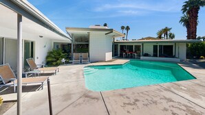 Une maison moderne dotée d’une piscine, d’un espace salon extérieur et de palmiers.