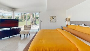Une chambre à coucher avec un grand lit, une télévision, un fauteuil et un tableau.