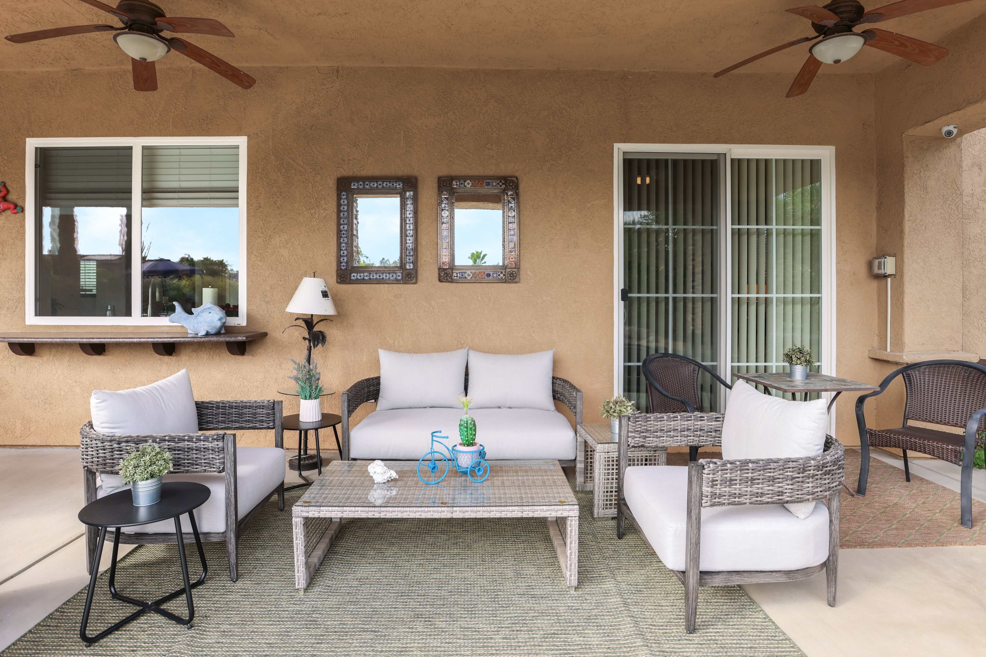 A patio area with wicker furniture, a white sofa, a coffee table, and ceiling fans.