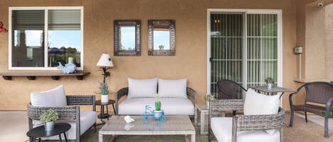 A patio area with wicker furniture, a white sofa, a coffee table, and ceiling fans.
