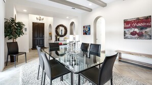 Un coin repas avec une table en verre et des chaises noires, un lustre et une guirlande accrochée au mur.