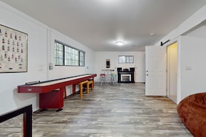A spacious room with a long table, a fireplace, and a door leading to another room. - Two-story home with game room, large deck, bbq grill, & yard (Lakeside)