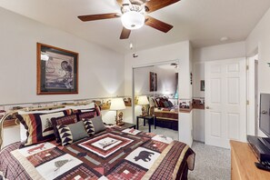 A bedroom with a bed, a ceiling fan, a framed artwork, a mirror, and a television. - Two-story home with game room, large deck, bbq grill, & yard (Lakeside)