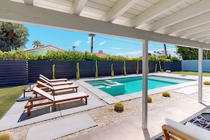 A covered outdoor area with a swimming pool, lounge chairs, and a cactus decoration. - Beautiful home with private pool, pool spa & open living space (Palm Springs)