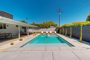 Un espace piscine extérieur moderne, agrémenté d’une pergola, de chaises longues et d’un jardin bien entretenu.