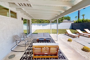 A covered patio with outdoor seating, including a sofa, chairs, and a bench. - Beautiful home with private pool, pool spa & open living space (Palm Springs)