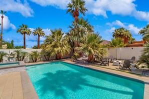 A clear blue swimming pool surrounded by palm trees and outdoor furniture. - Jewel on a double lot with a private pool, spa, and resort like yard (La Quinta)