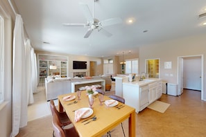 A modern open-plan living area with a dining table set for six, a kitchen, and a living room with a sofa and TV. - Palm Desert retreat with private pool, fireplace, & W/D & Pet Friendly (Palm Desert)