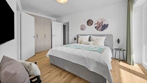 Ein modernes Schlafzimmer mit einem Bett, einem Nachttisch, einer Wandleuchte und einer Tür.