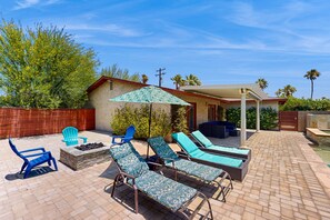 Eine Außenpatio mit Lounge-Möbeln, einem Feuerkorb und einem Poolbereich.
