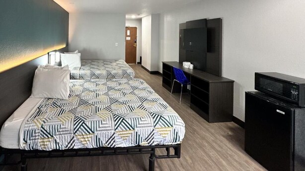 Habitació d'hotel amb un llit gran, televisió, escriptori i microones.