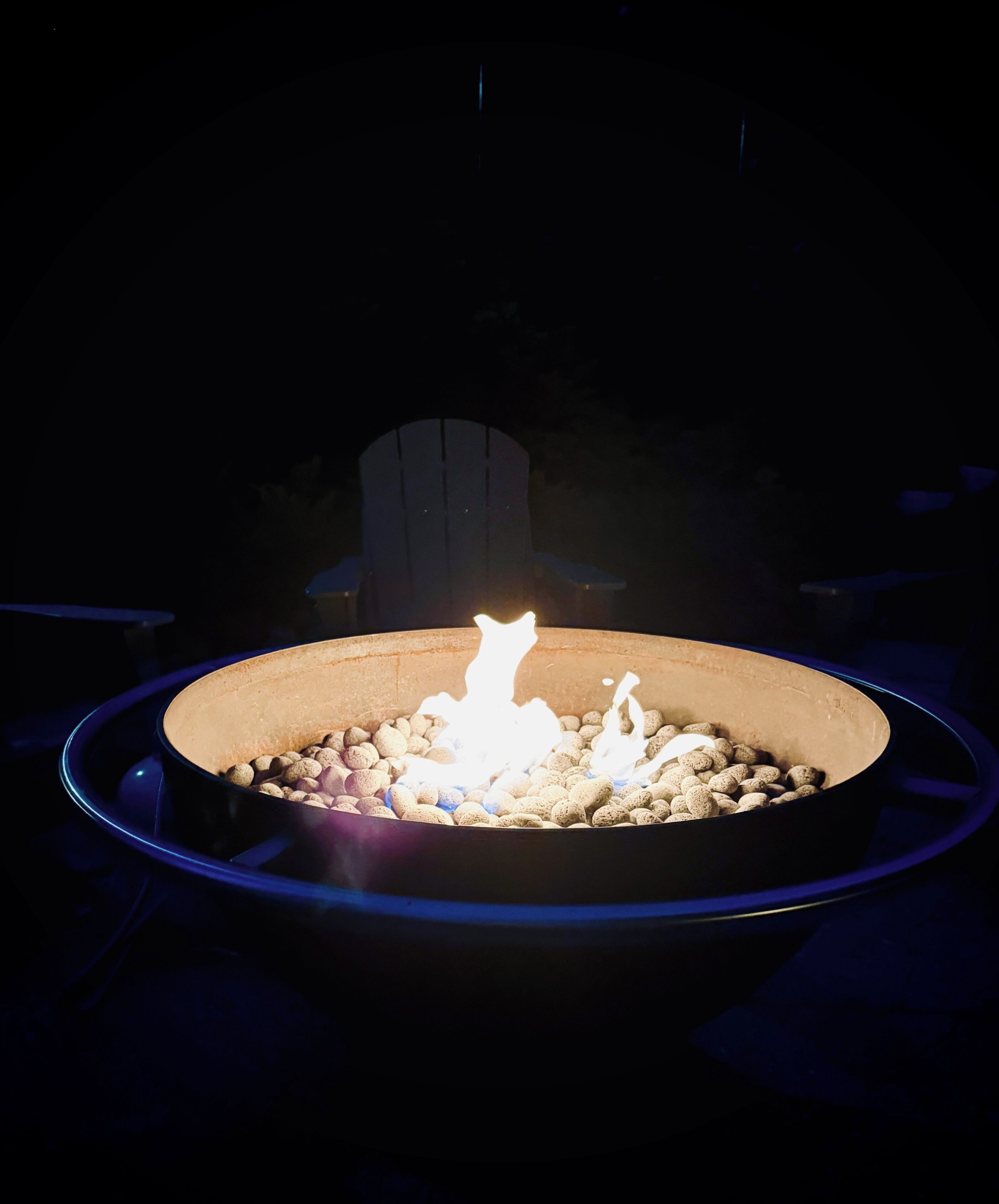 Ein runder Feuerkorb mit brennendem Holz, umgeben von Dunkelheit.