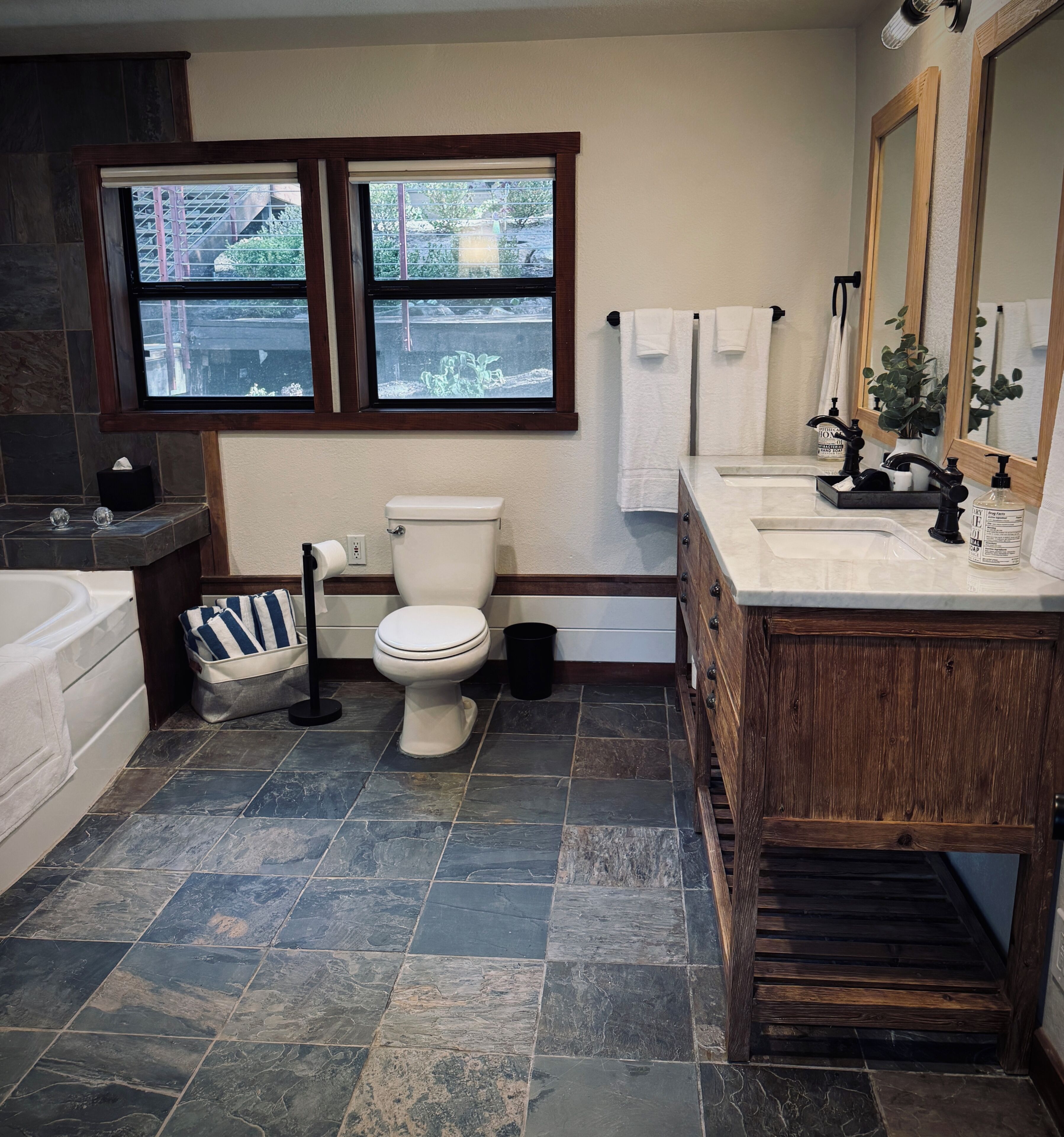 Un baño con inodoro, lavamanos, bañera y ventanas.