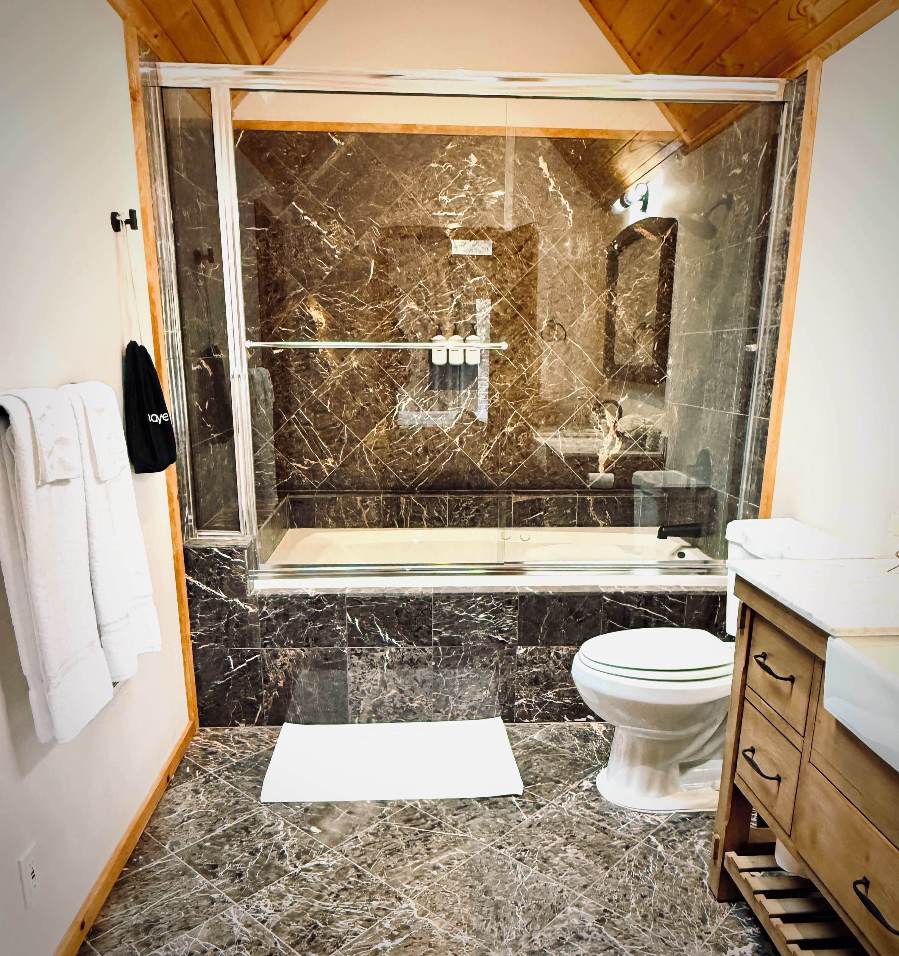 A bathroom with a glass-enclosed shower, a toilet, and a vanity with drawers.