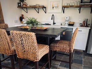 Une cuisine moderne avec une table en bois foncé, des chaises en osier et une machine à café.