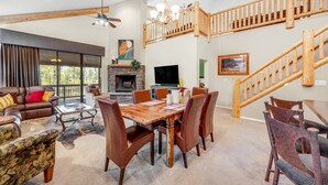 A spacious living area with a fireplace, a dining table, and a staircase. - Hideaway in the pines with pool table, covered deck, fireplace, grill, & W/D (Pinetop)