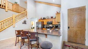 A kitchen with wooden cabinets, a stainless steel refrigerator, and a microwave. - Hideaway in the pines with pool table, covered deck, fireplace, grill, & W/D (Pinetop)