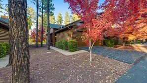 A log cabin with a gravel driveway and a tree with red leaves. - Hideaway in the pines with pool table, covered deck, fireplace, grill, & W/D (Pinetop)