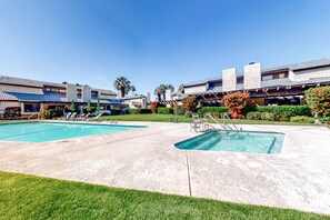 A pool area with two pools, lounge chairs, and a covered patio. - Beautiful Family Home w/Shared Pool/Spa, Firepit, Central AC, & Mountain Views (Palm Springs)