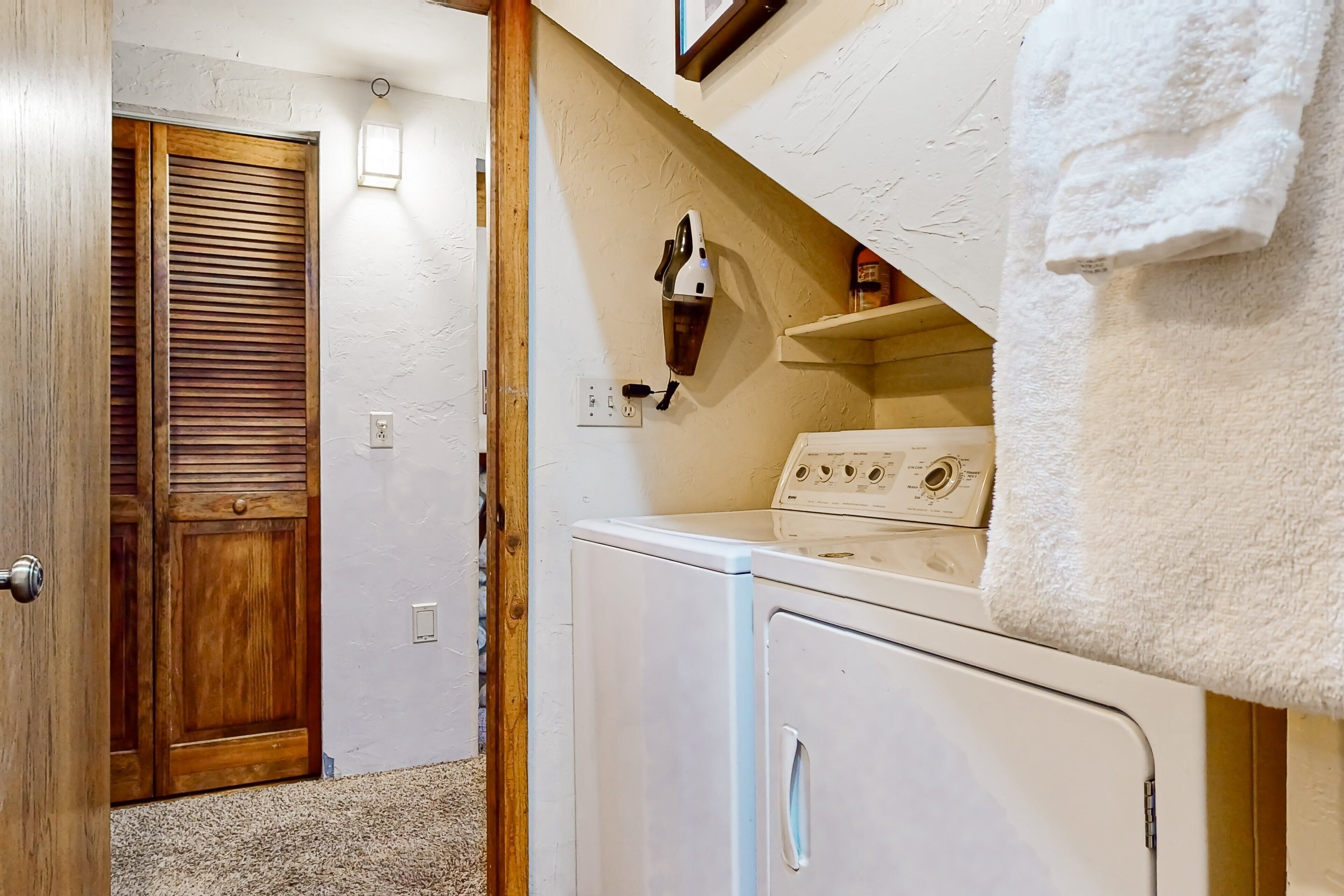 A laundry room with a washing machine, a dryer, and a wooden door.